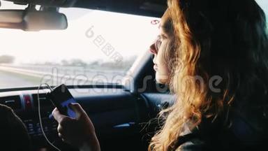 一个年轻的女人坐在副驾驶座上。 手里拿着手机.. 去汽车旅行，很好